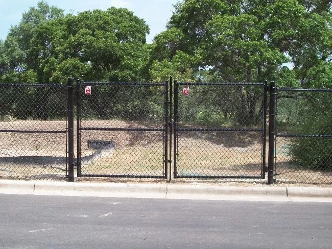 Black chain link double swing gate at a roadside entrance