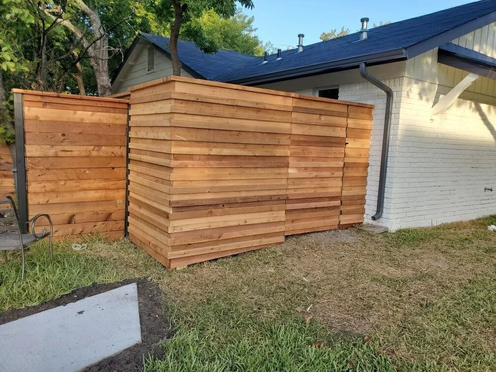 Horizontal cedar fence screening the side yard of a white brick home