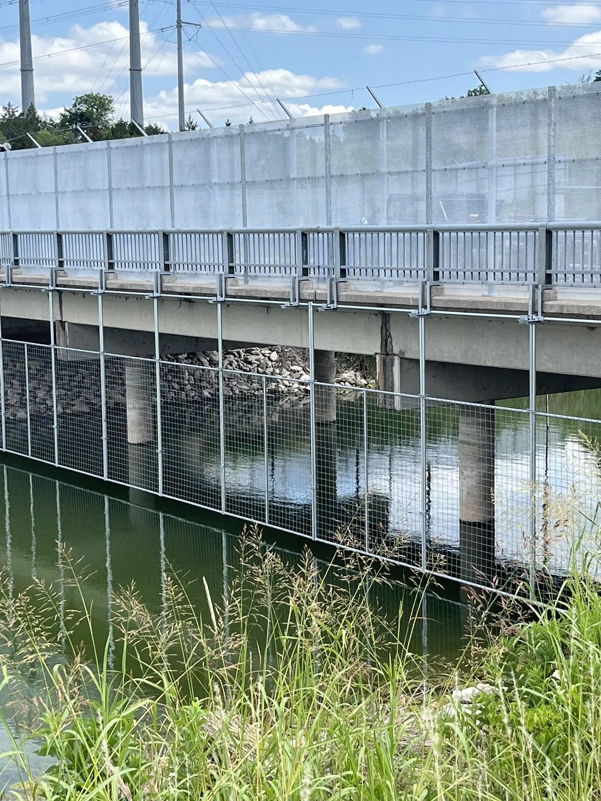 Chain link screen panels running along the edge of a bridge deck