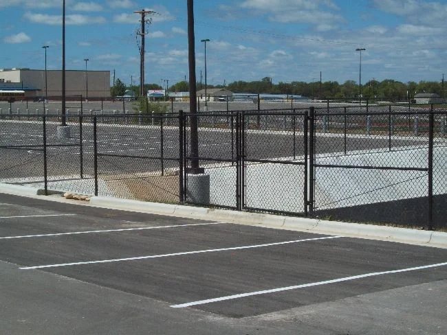 Black chain link fence and gates around a commercial parking area