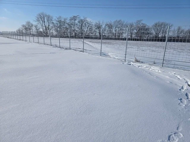 Chain link fence crossing a snow covered field after a Central Texas freeze