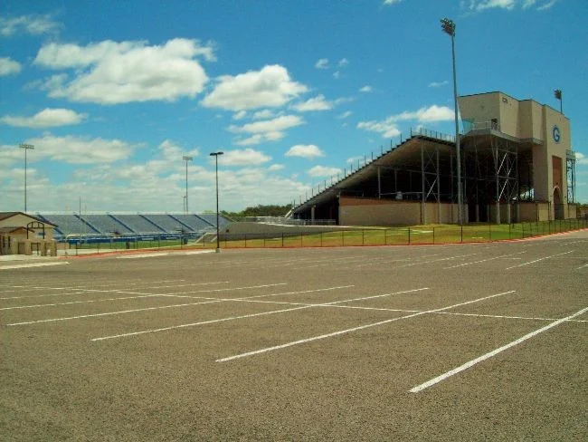Chain link perimeter fencing at a school athletic field and grandstand