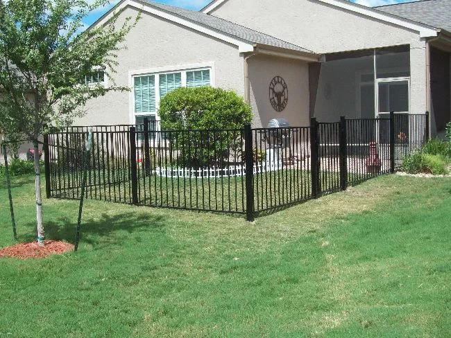 Ornamental iron fence enclosing the front yard of a stucco home