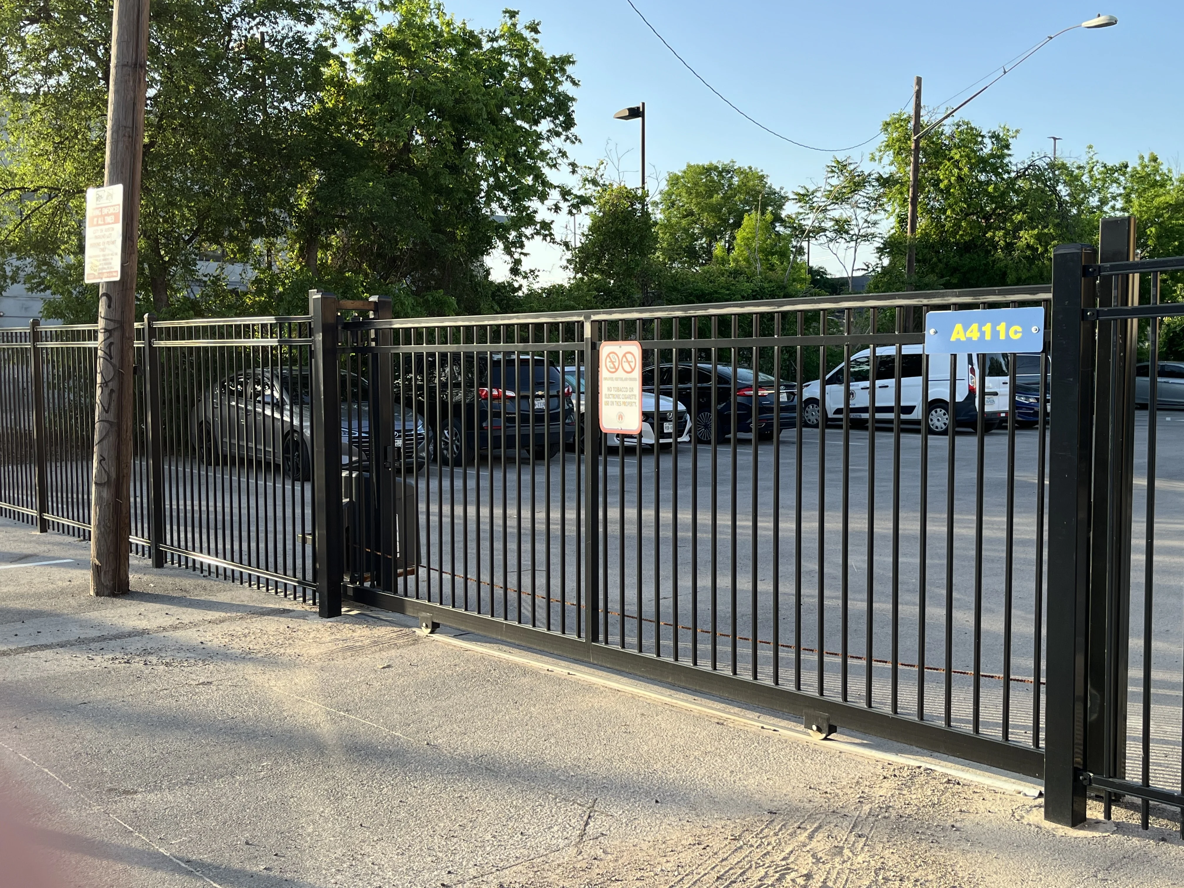 Black ornamental iron fence and sliding gate securing a commercial parking lot