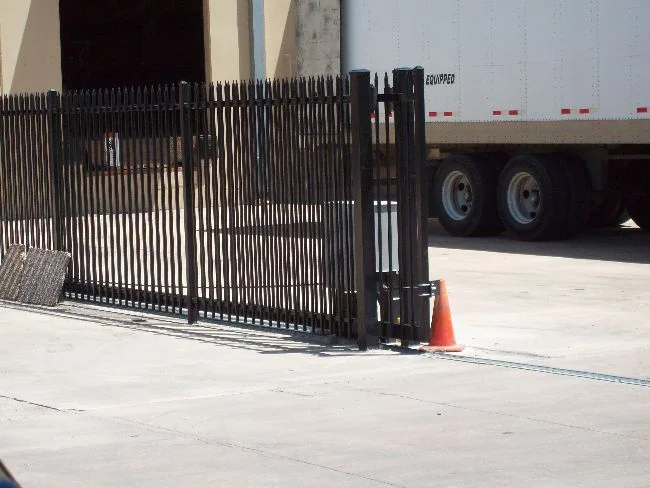 Black iron slide gate at a loading dock with a semi trailer beyond