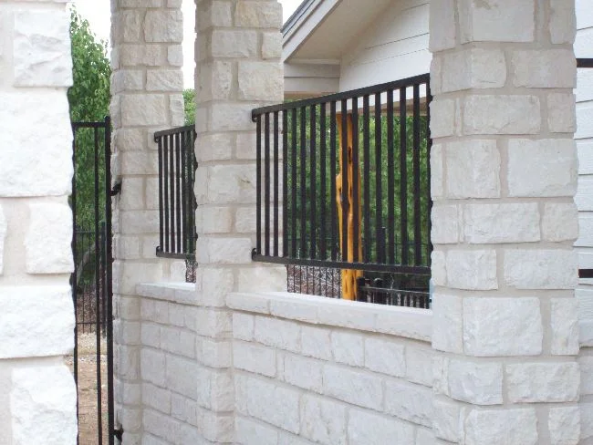 Ornamental iron fence and gate set between white stone columns at a residence
