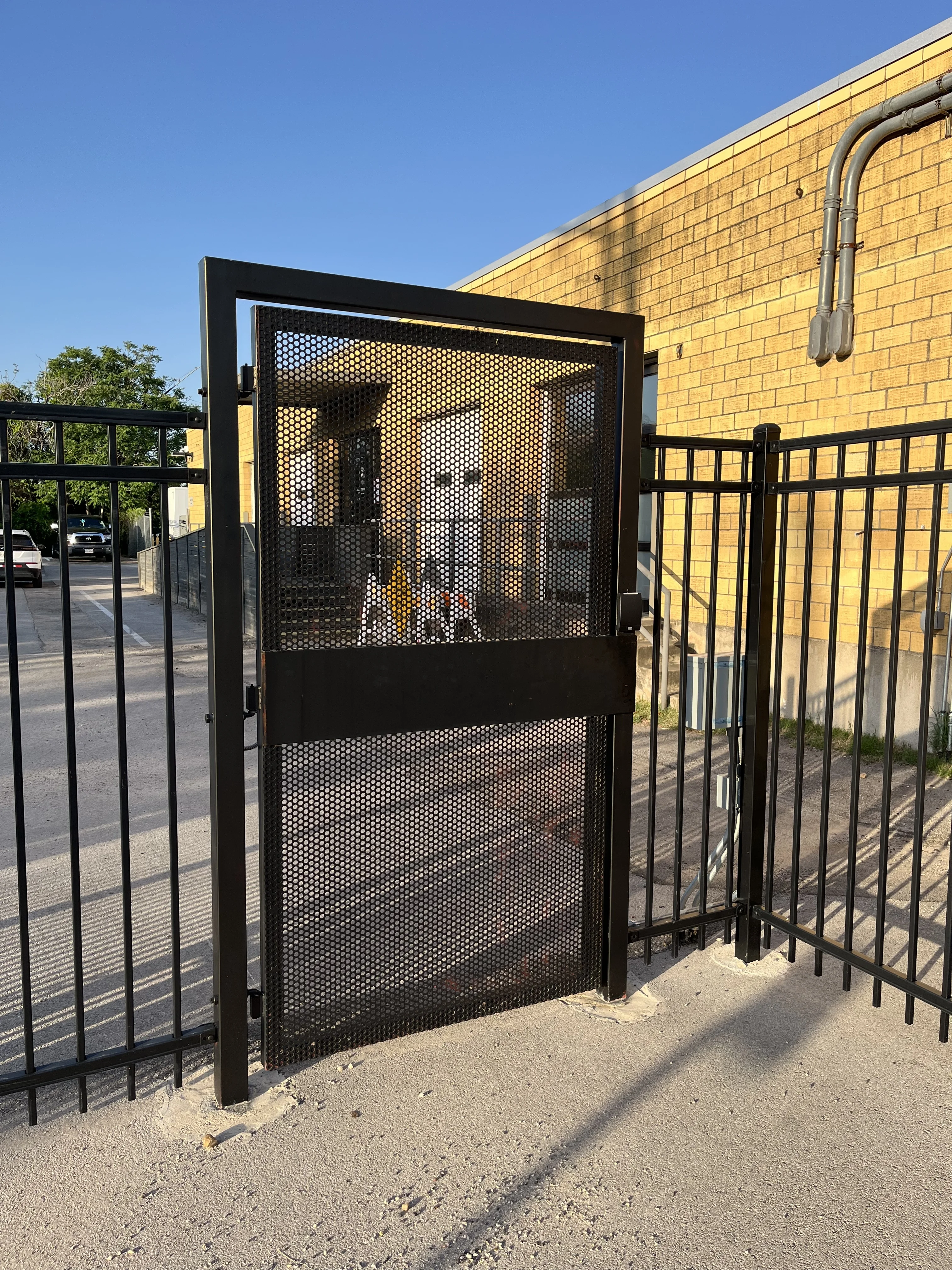 Ornamental iron fence with a mesh pedestrian gate at a commercial building