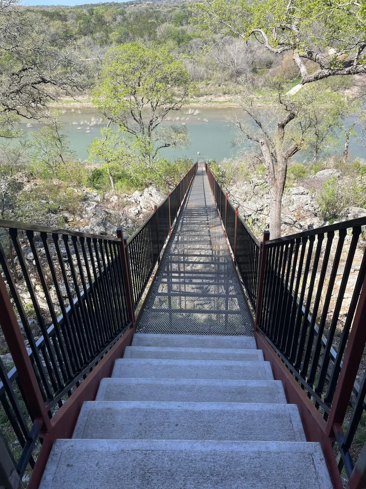 Steel suspension footbridge with black iron railings and concrete stair treads