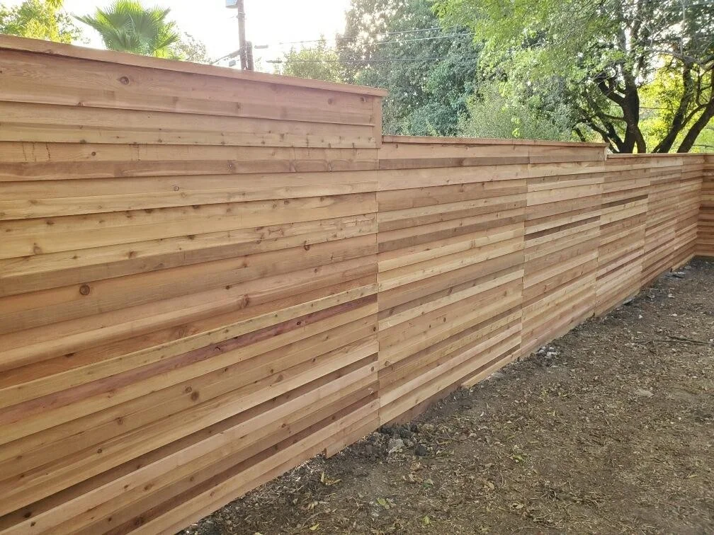Horizontal cedar privacy fence stepping down a graded slope