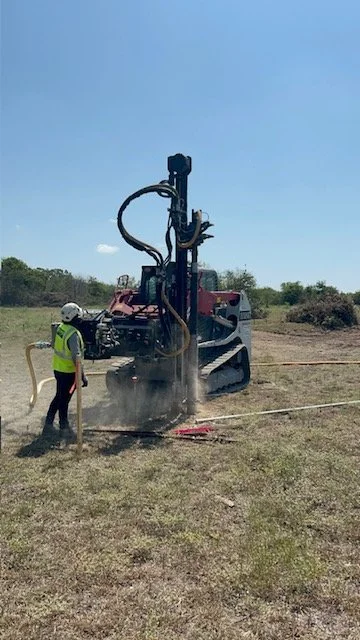 Track mounted post driver setting fence posts in an open field