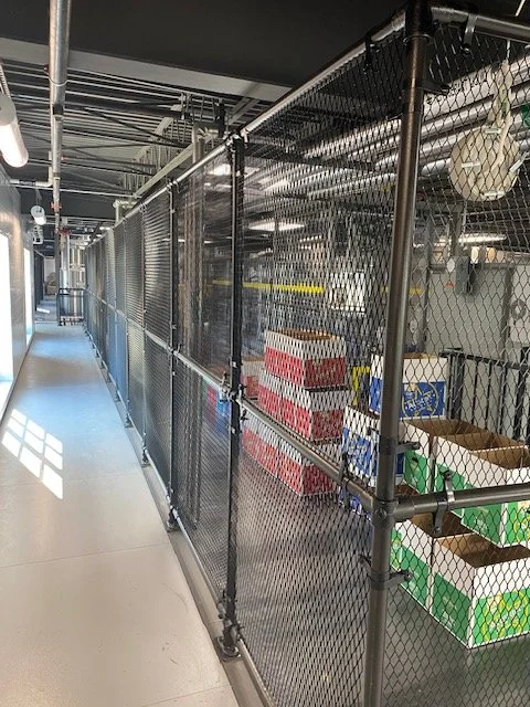 Chain link security caging enclosing stocked shelving inside a warehouse