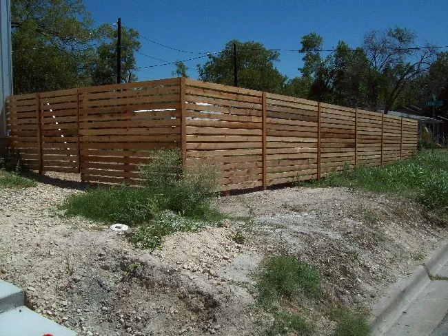 Horizontal cedar privacy fence around a sloped and freshly graded backyard