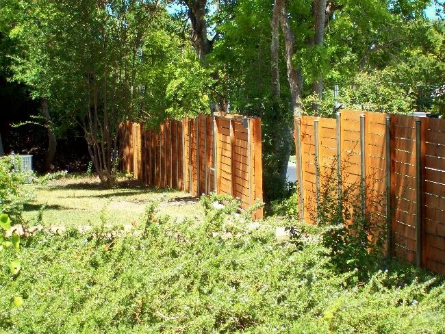 Cedar privacy fence panels set among trees in a landscaped yard