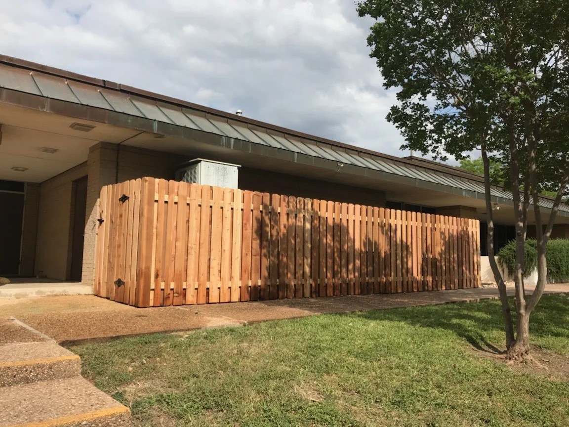 Vertical cedar picket fence screening the carport of a mid century home